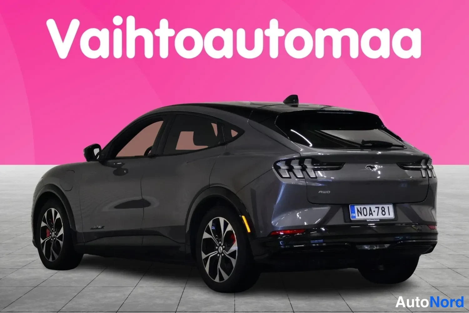 Takaviisto: Tummanharmaa Ford Mustang Mach-E takaa kolmannekselta vasemmalle, rekisteritunnus, peräosassa AWD-merkintä.