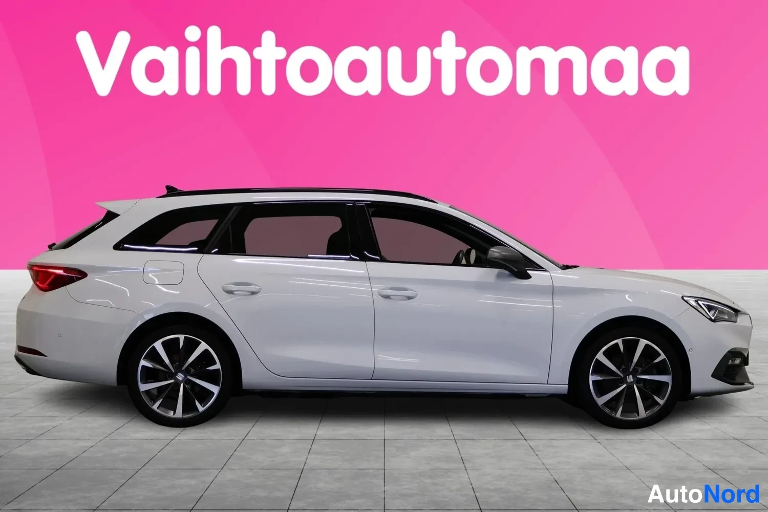 Etuviisto, nokka oikealle: Seat Leon Sportstourer Farmari kyljestä valkoinen