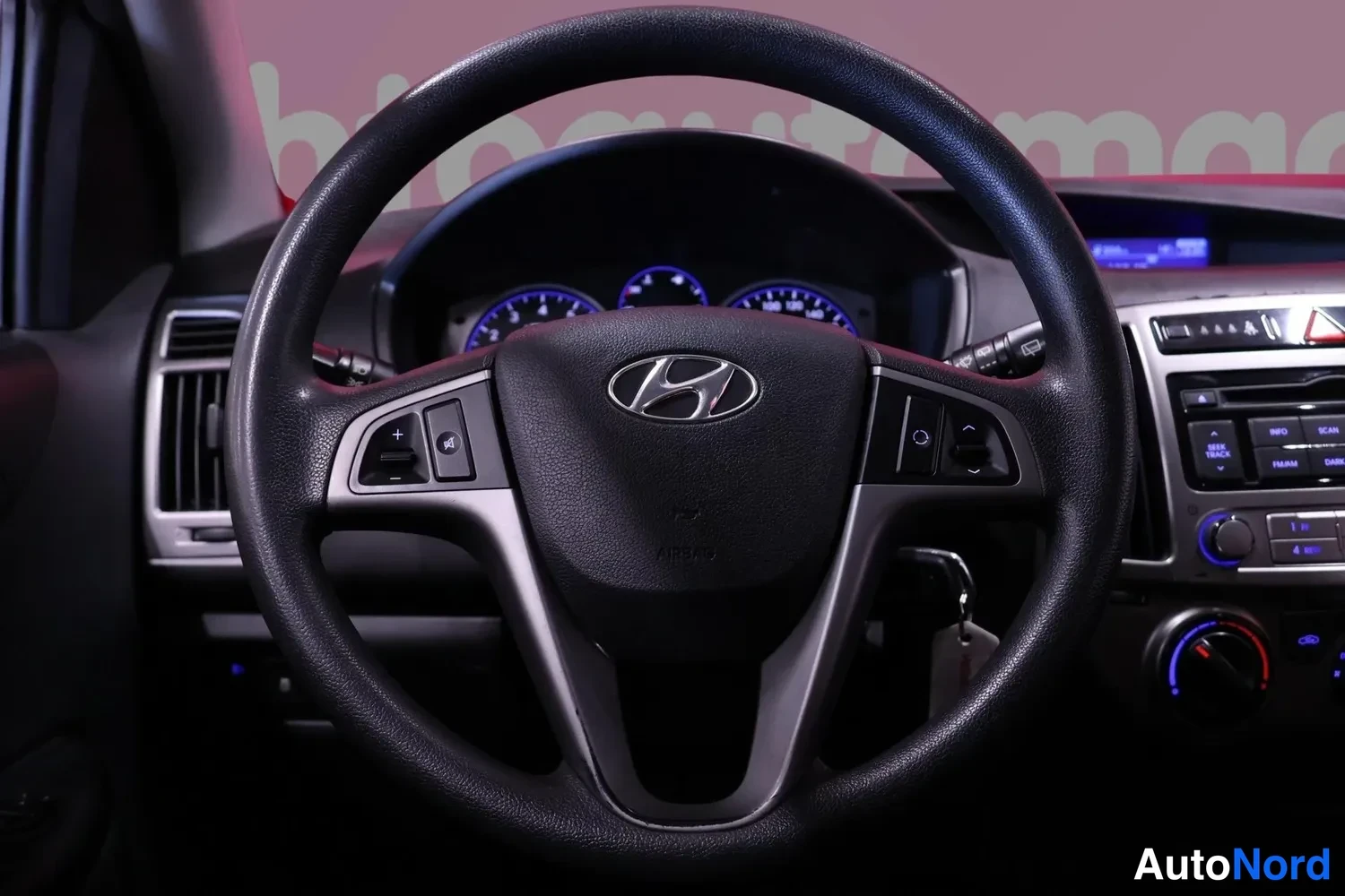 Muu: Ohjauspyörän lähikuva Hyundai-merkillä ja multisäädöillä, mittaristo taustalla.