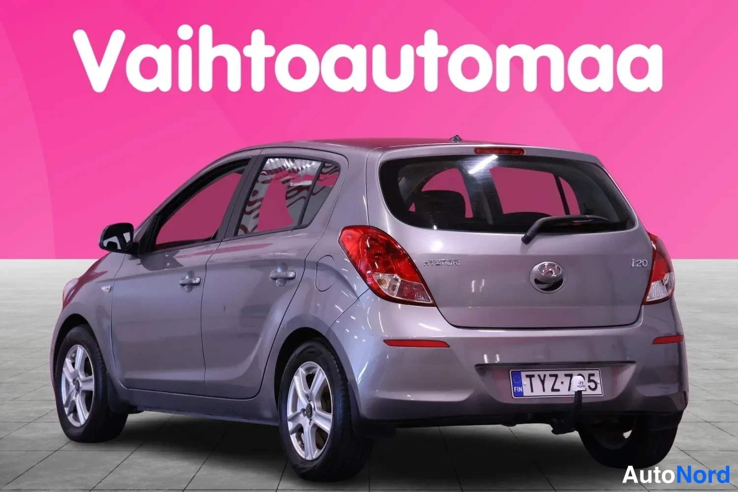 Takaviisto: Silver-grey Hyundai i20 rear three-quarter view showing the tailgate with 'i20' and '1.4 CRDi' badges, rear lights, tow bar, rear wheel, and a Finnish licence p