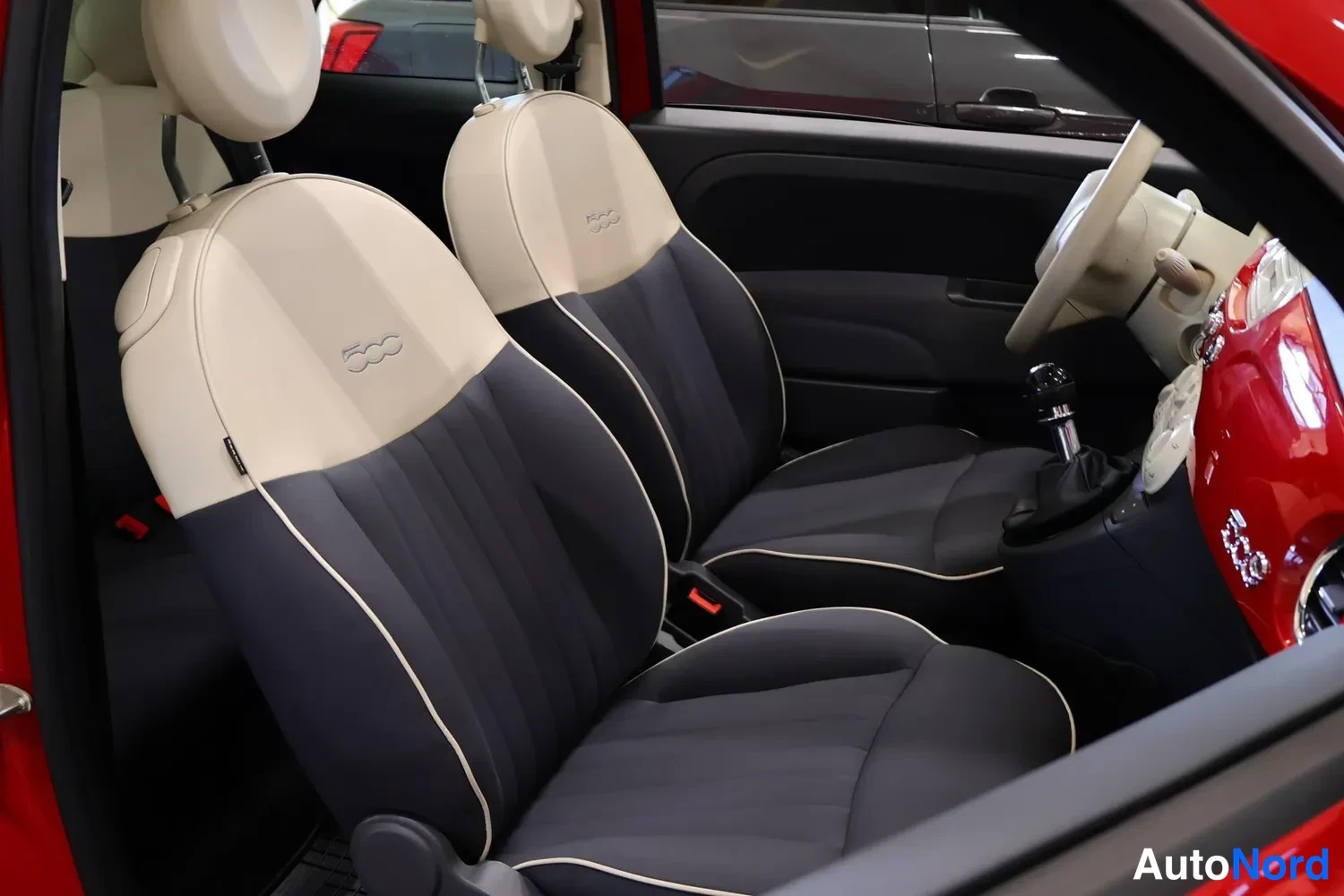 Muu: Fiat 500C:n etuistuimet tummansinisellä istuinosalla ja beigeillä selkänojilla, kartingokset ja ovipaneeli näkyvissä.