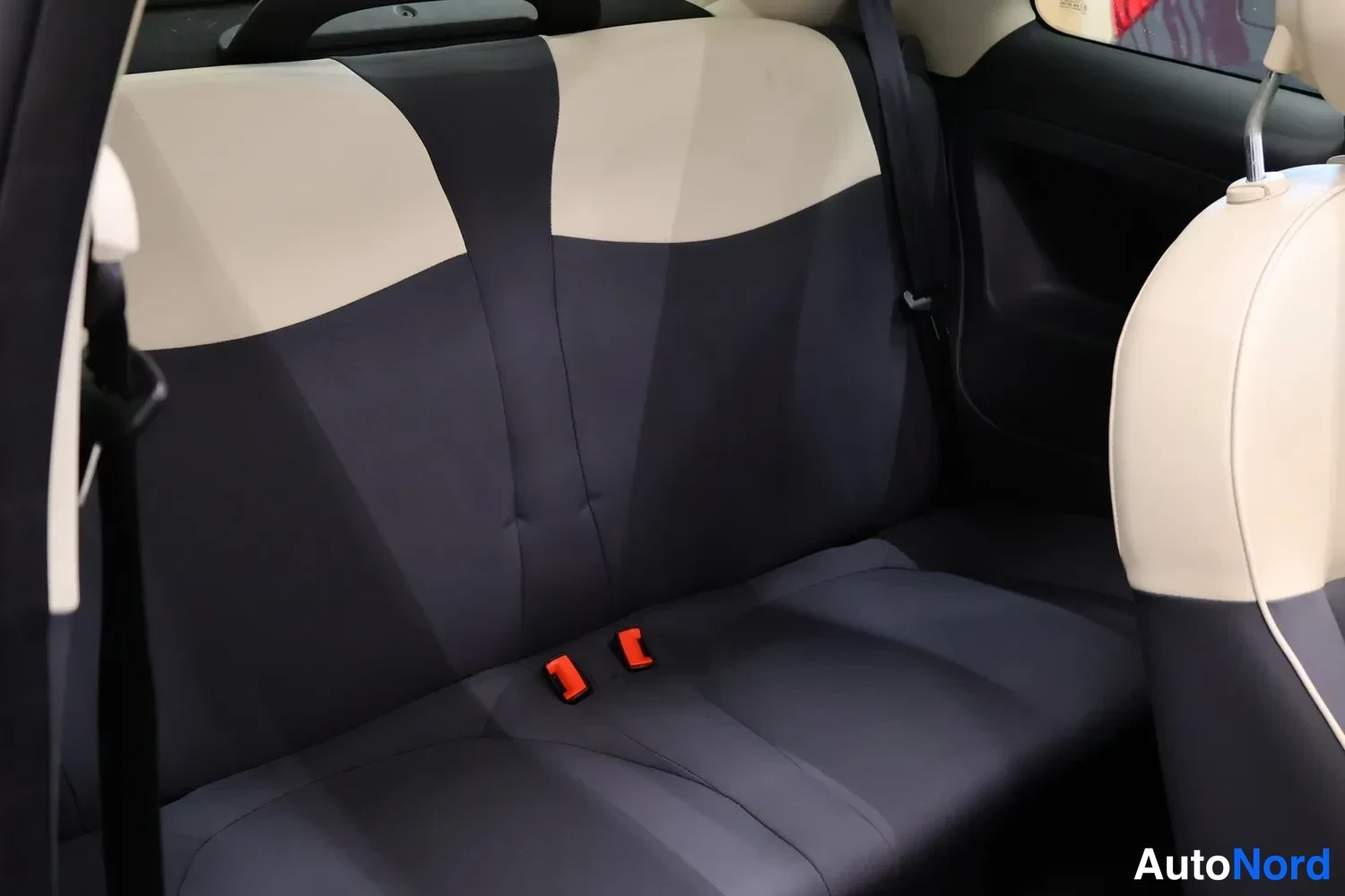 Muu: Fiat 500C:n takapenkkki tummansinisellä verhoilulla ja beigeillä selkänojilla, turvavyönsoljet näkyvissä.