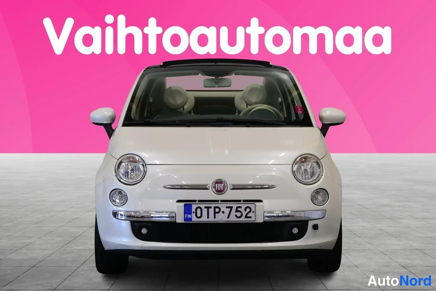 Edestä: Valkoinen Fiat 500C suoraan edestäpäin, rekisteritunnus, avattava kangaskatto, Fiat-merkki keulassa ja pyöreät ajovalot.
