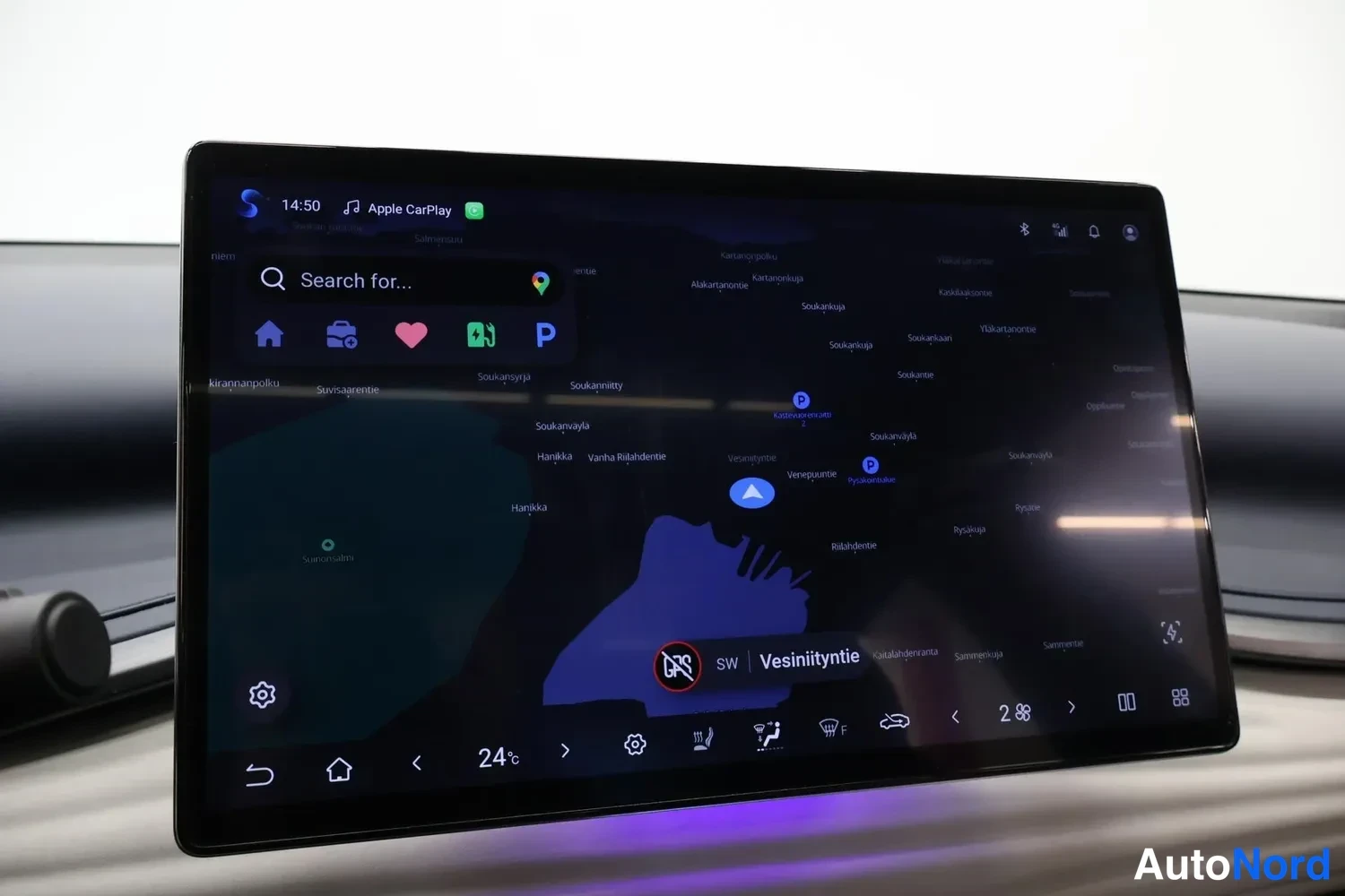 Yksityiskohta: Keskikonsolin suuri kosketusnäyttö, jolla näkyy Apple CarPlay ja karttanavigointi.