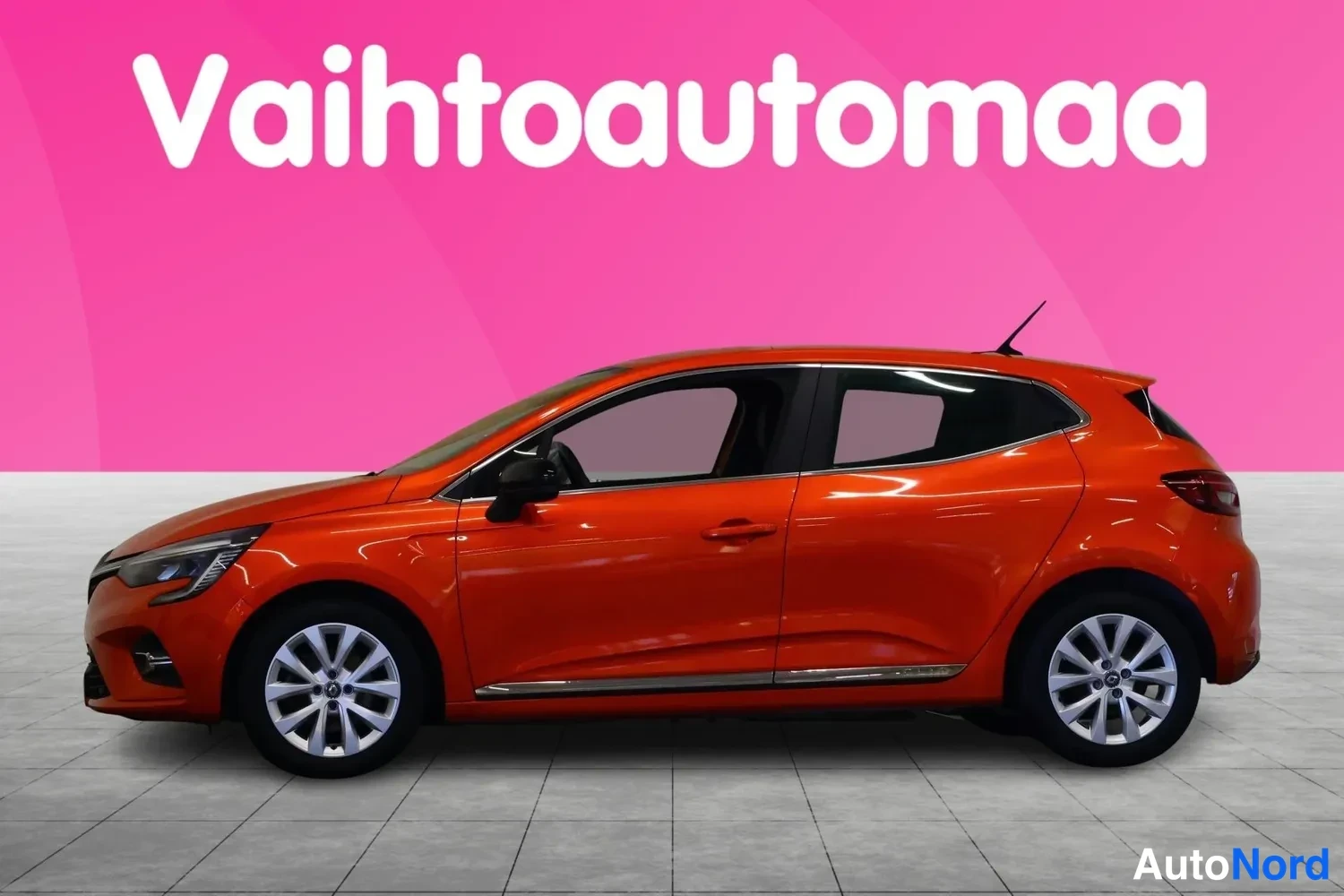 Etuviisto, nokka vasemmalle: Oranssinsuuntaisella maalilla oleva Renault Clio -henkilöauto sivulta kulmasta kuvattuna, keula vasemmalla.