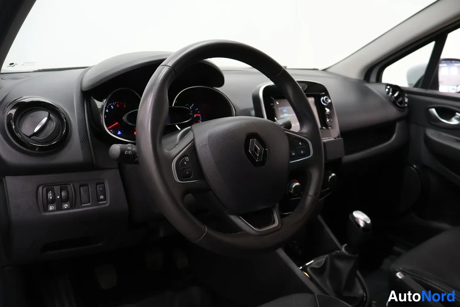 Yksityiskohta: Renault-logollinen ohjauspyörä, analogiset mittarit, kosketusnäyttö keskikonsolissa ja manuaalivaihteistovyöhyke.