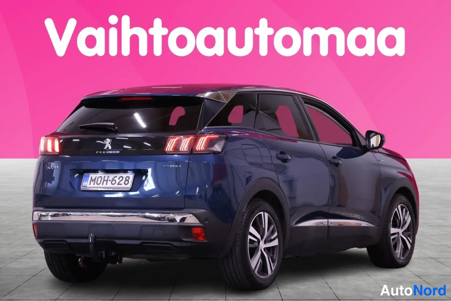 Takaviisto: Tummansininen farmillinen henkilöauto takakulmasta, perä vasemmalla, rekisteritunnus, vetokoulu näkyy.