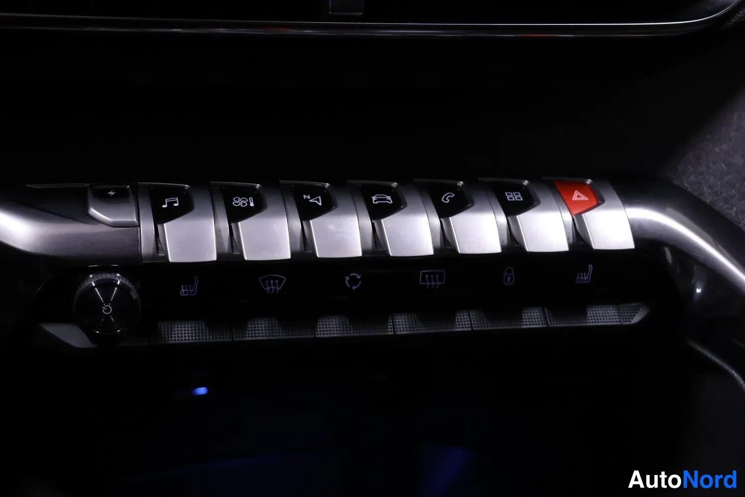 Yksityiskohta: Close-up of centre console switch panel with silver toggle switches and climate control dials. Switches include hazard lights (triangle), heated seat icons, and