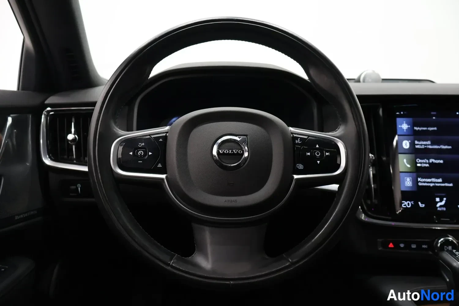 Muu: Volvo-ohjauspyörä kojelautaa vasten, mukana monitoiminapit, merkkivalo ja osittain näkyvä keskusnäyttö.