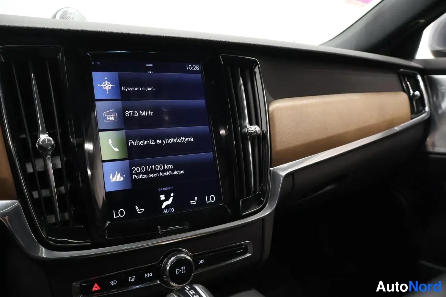 Muu: Ryhmittelyllä oleva kojelaudan keskinäyttö, jossa näkyy radio 87.5 MHz, puhelun yhdistäminen ja kulutus 20,0 l/100 km.