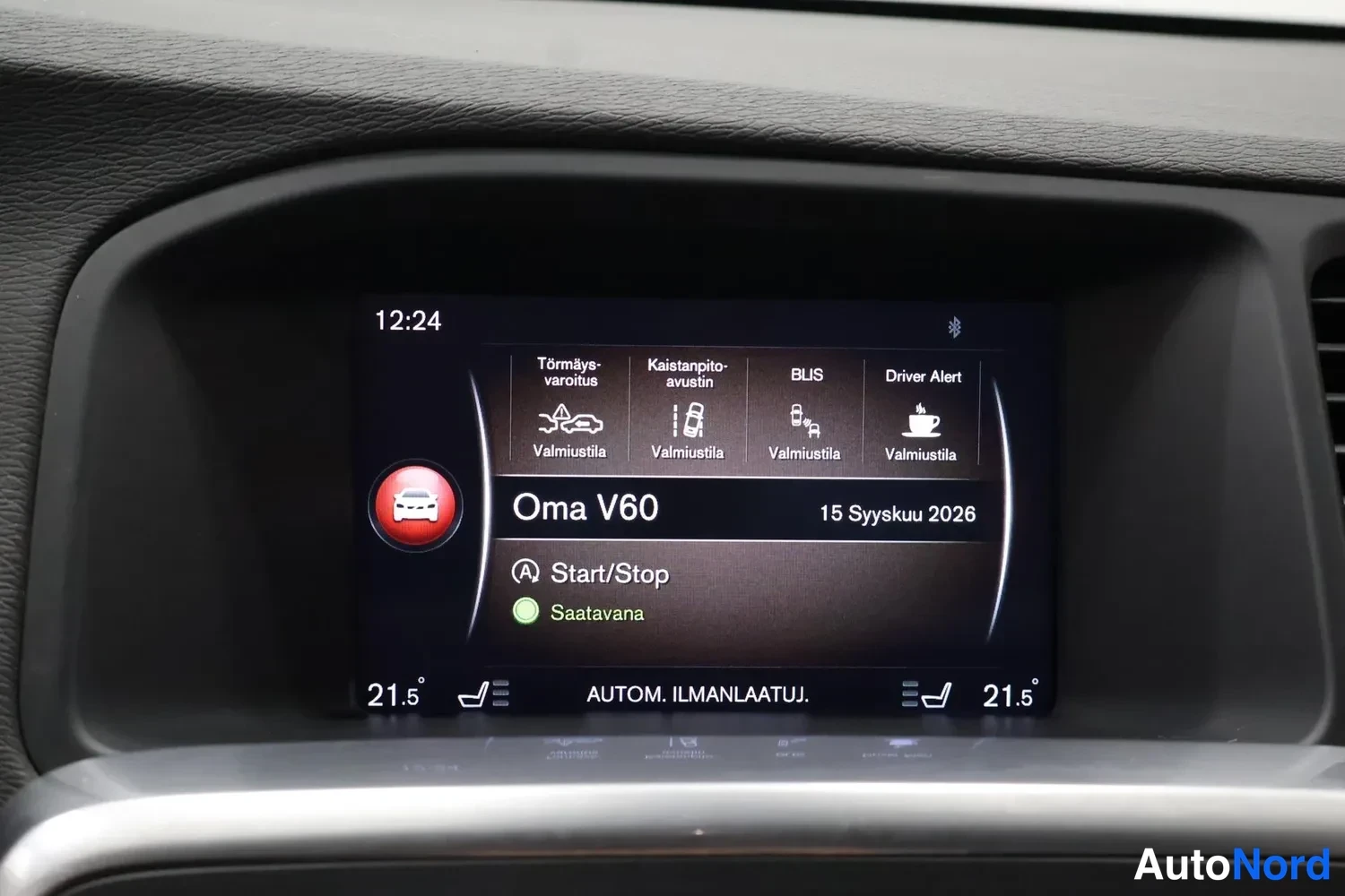 Yksityiskohta: Kojelaudan infonäyttö näyttää kellonajan 12:24, turvallisuusjärjestelmien valmiustilat (Törmäys-varoitus, Kaistapito-avustin, BLIS, Driver Alert), Oma V60 -prof