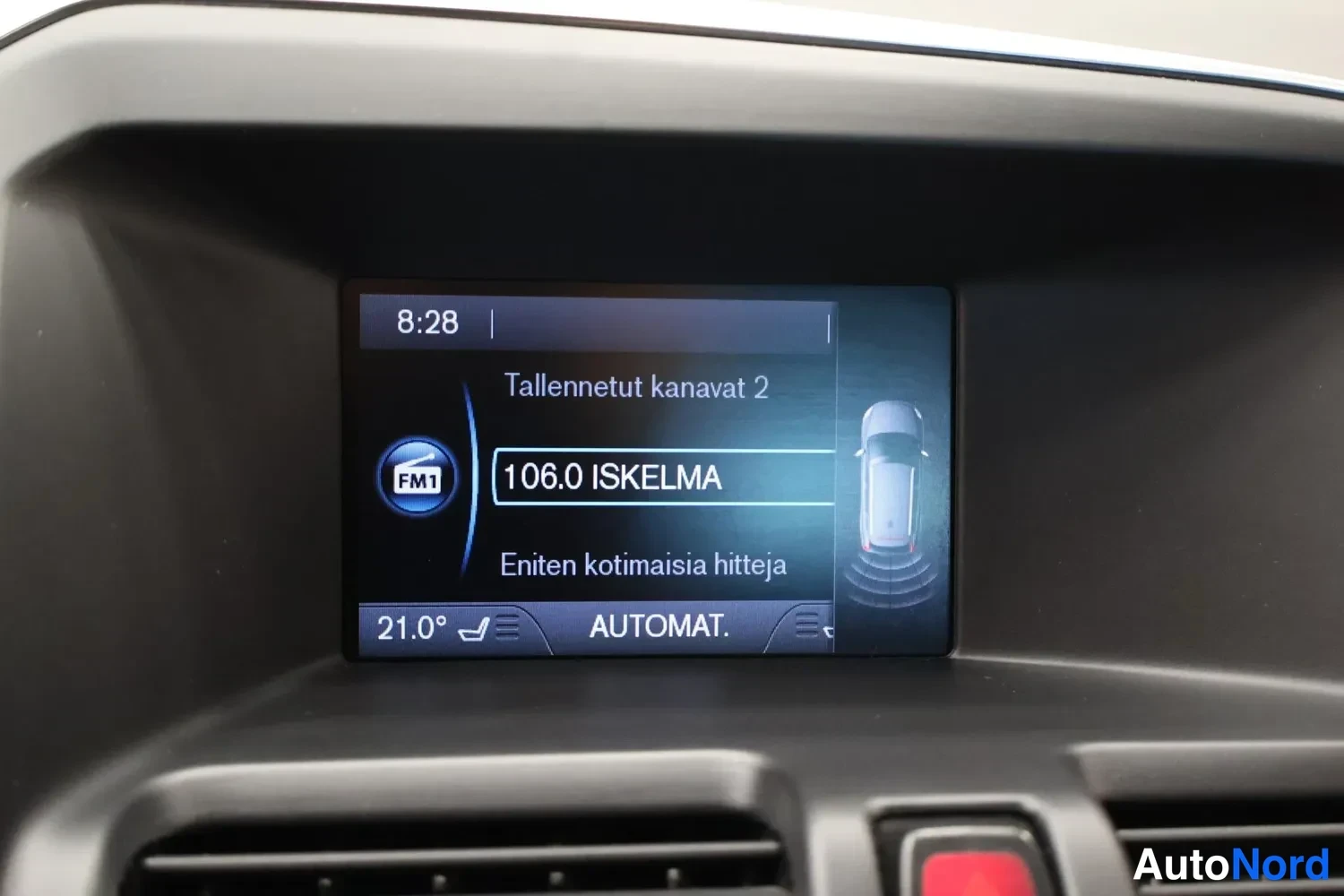 Muu: Kojelaudan infonäyttö radiotilassa: 106.0 ISKELMA, Tallennetut kanavat 2, teksti Eniten kotimaisia hittejä ja parkkitutkan autoikonit.