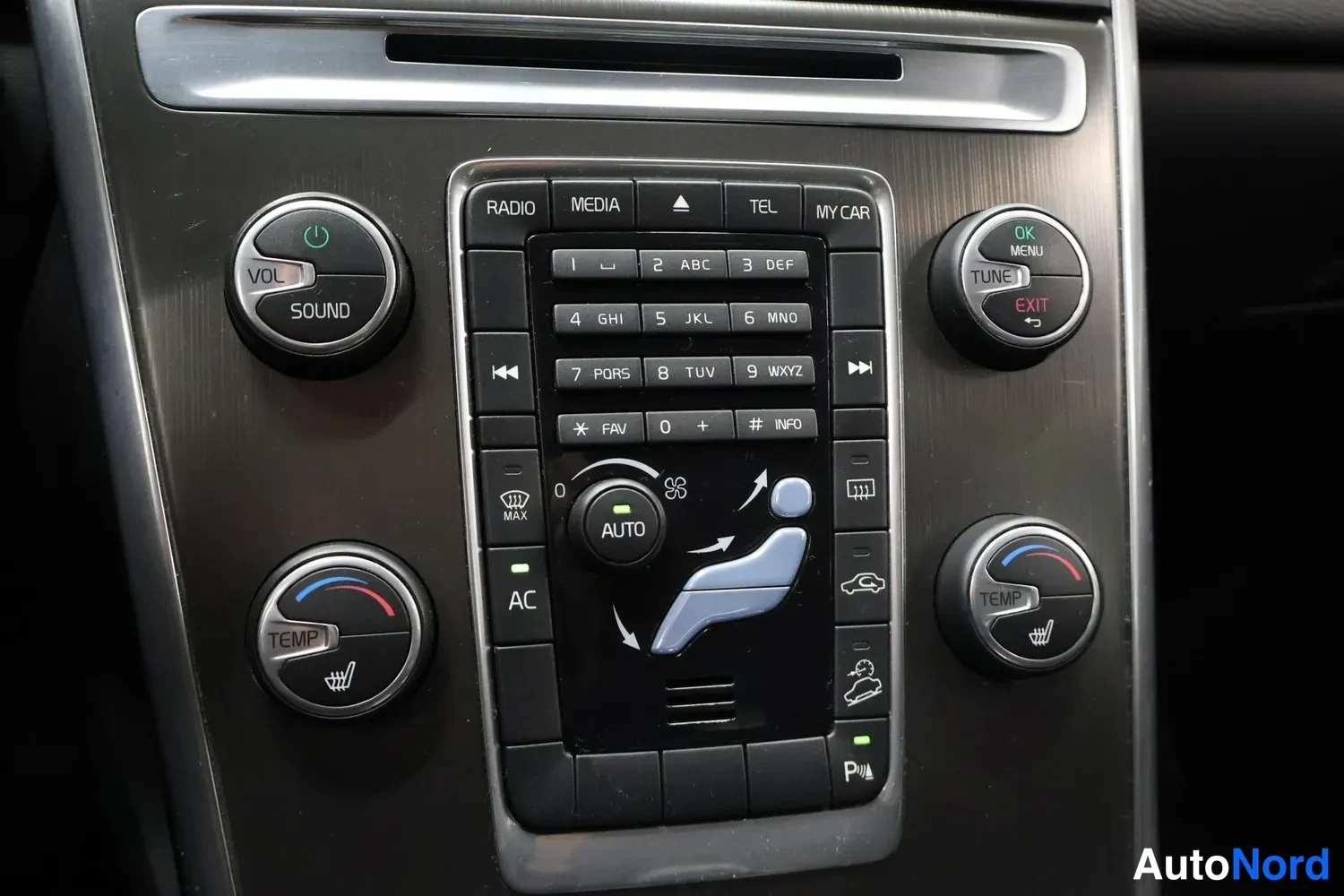 Muu: Kojelaudan keskuspaneeli lähikuvassa: RADIO-, MEDIA-, TEL- ja MY CAR -painikkeet, numeronäppäimistö, VOL/SOUND- ja TUNE-rullat OK/MENU-merkeillä, kaksi TEMP-läm