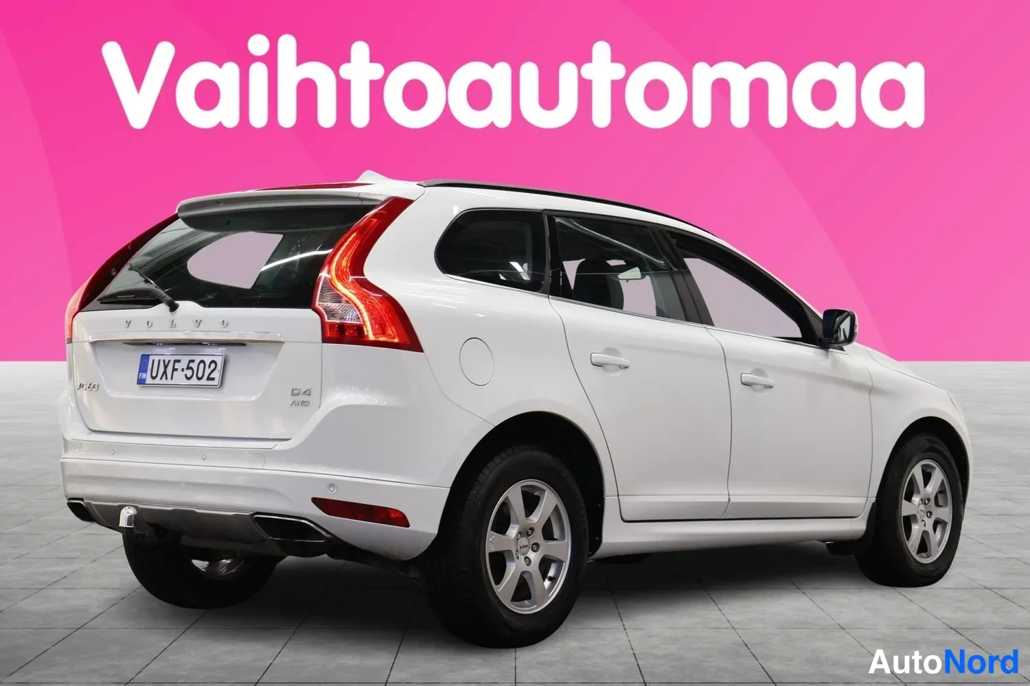 Takaviisto: Valkoinen farmarimallinen auto takaviistosta vasemmalta kuvattuna, rekisteritunnus, Vahtoautomaa-taustalla.