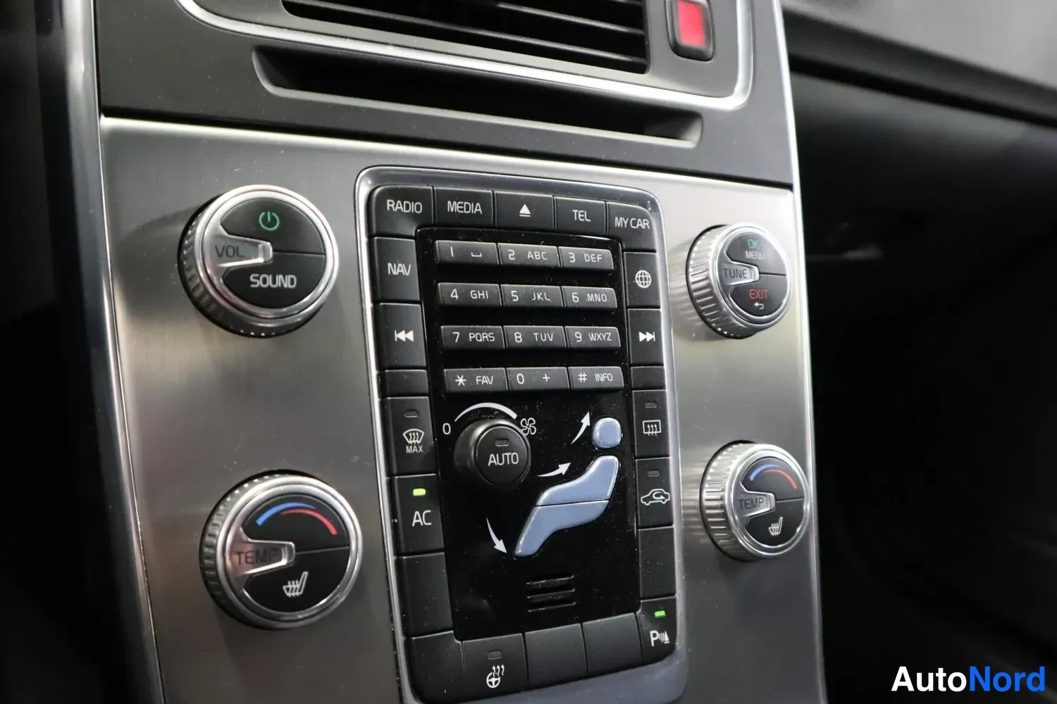 Yksityiskohta: Autoradion ja ilmastoinnin keskuspaneeli: volyymin ja temperaturen säätörullat, näppäimet RADIO, MEDIA, TEL, NAV, AC ja AUTO.