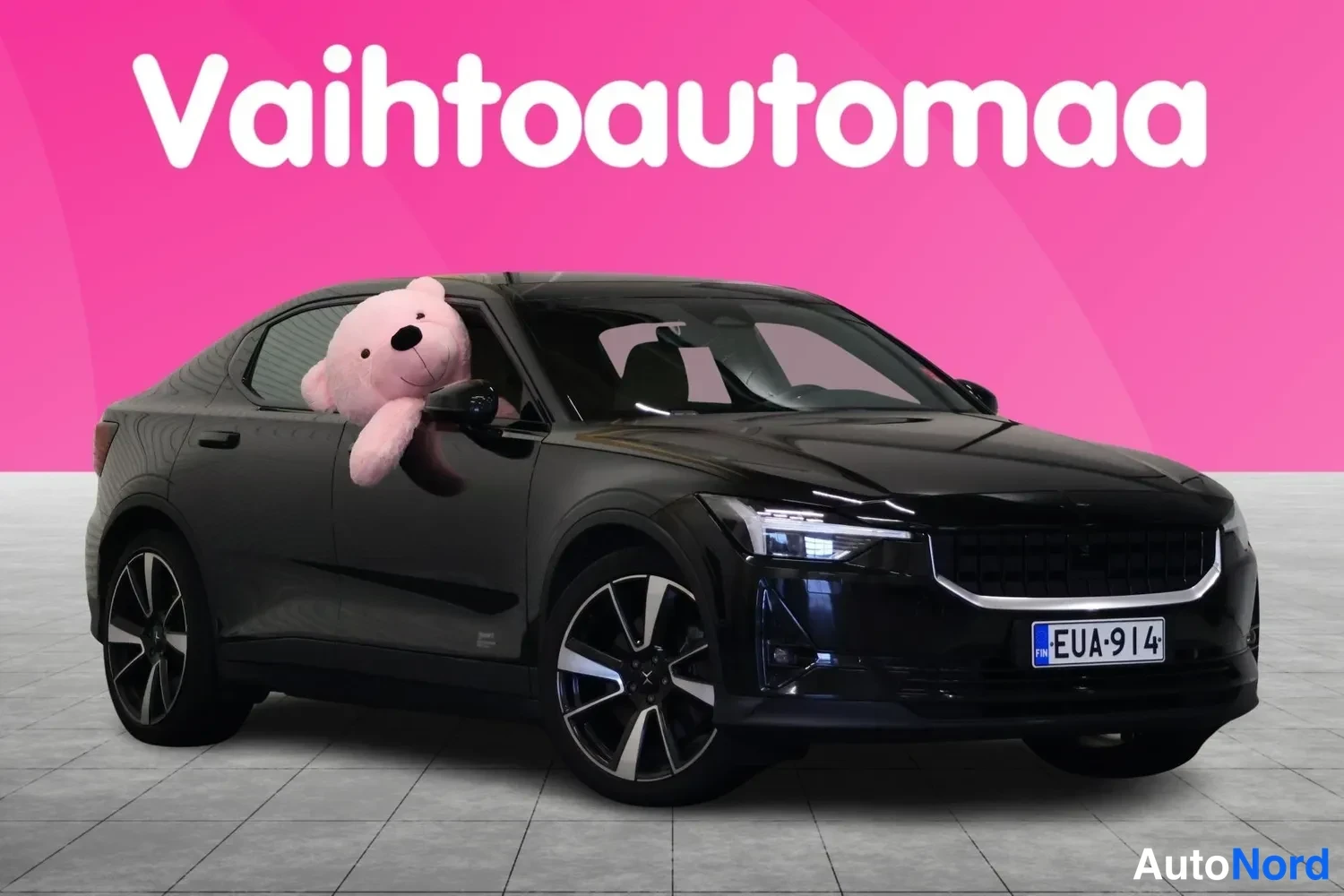 Etuviisto, nokka oikealle: Mustan Polestar 2:n etunurkkakuva pehmisellä nallella ikkunassa, rekisteri.