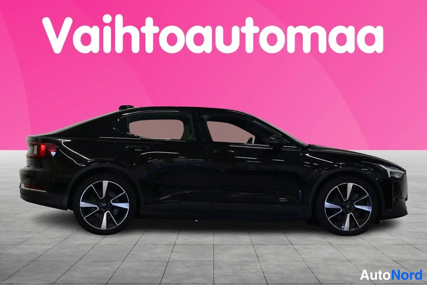 Sivulta: Mustan automallin sivukuva vasemmalta, hopeiset vanteet, vaaleanpunainen tausta.