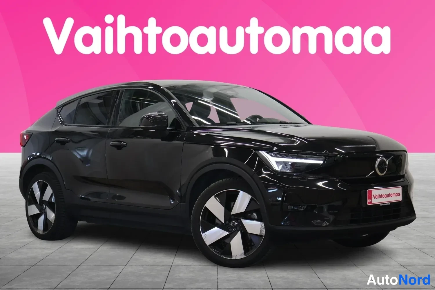 Etuviisto, nokka oikealle: Musta Volvo C40 kokonaisuudessaan etu kolmasosan kuvakulmasta, keula oikealla, vaaleat LED-ajovalot ja suuret vanteet.