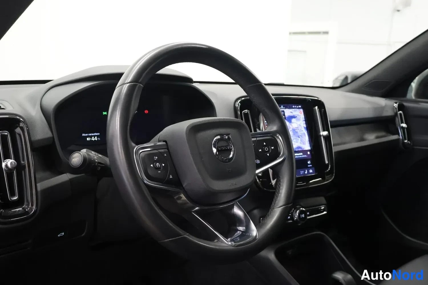 Yksityiskohta: Volvo-ohjaamo kulmasta kuvattuna: ohjauspyörä, puoliksi näkyvä digitaalinen mittaristo ja keskinäyttö karttanäkymällä.