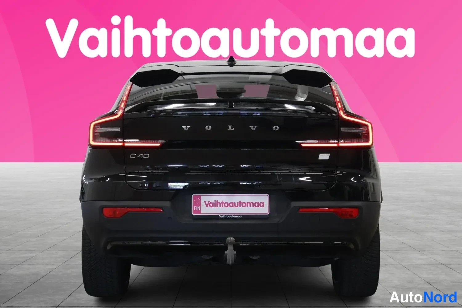 Takaa: Mustan Volvo C40:n takanäki: LED-takavalot ja VOLVO-merkintä takaluukissa, Vaihtoautomaa-kyltti rekisteritunnuspaikalla ja vetokoukku puskurissa.