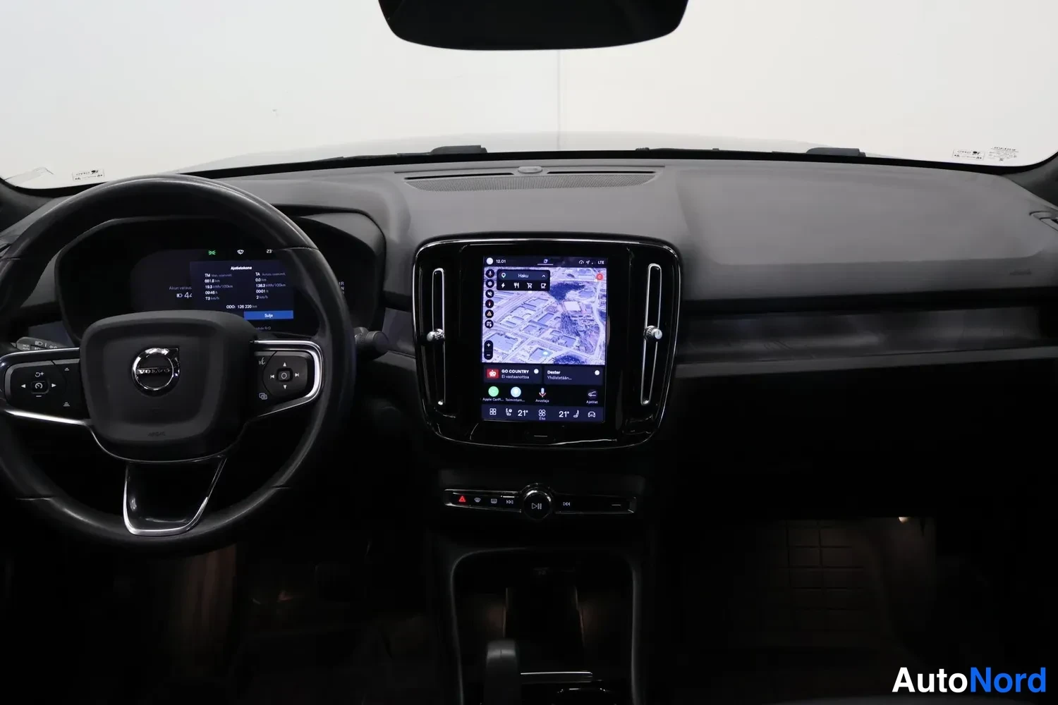 Yksityiskohta: Ohjaamo vasemmalta: Volvo-ohjauspyörä, digitaalinen mittaristo ja pystysuora keskinäyttö kartalla, tumma kojelauta.