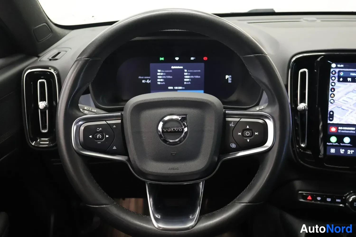 Yksityiskohta: Lähikuva Volvon ohjauspyörästä, keskellä Volvo-logo ja airbag-teksti, vasemmalla pikavaihteistotangon ympäristö.