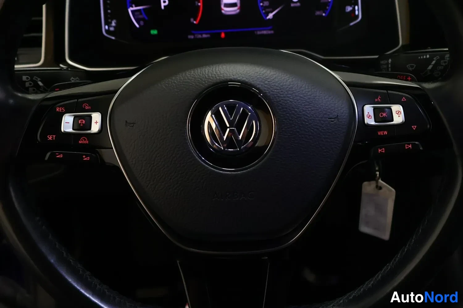 Muu: Volkswagenin ohjauspyörä, jossa on VW-merkki, AIRBAG-teksti, nappiryhmät (RES, SET, MODE, OK, VIEW) ja avain ripustettuna.