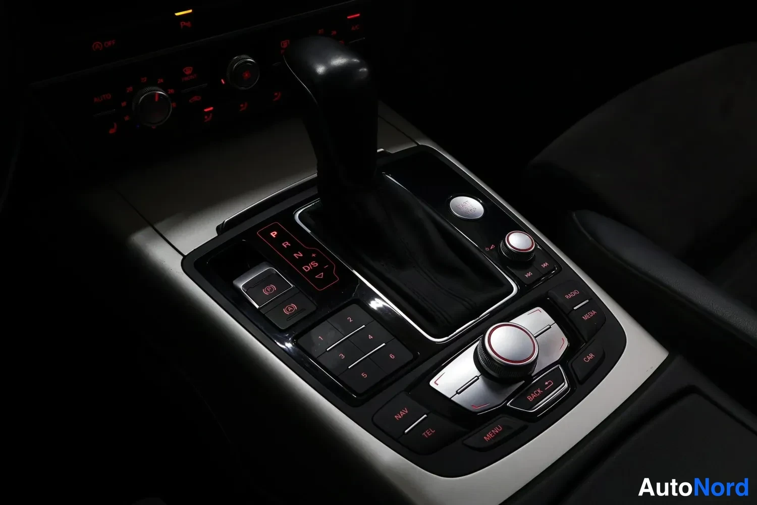 Yksityiskohta: Kesk console lähikuva automaattivaihteiston valitsimesta ja MMI-järjestelmän säätimestä, jonka ympärillä on NAV-, TEL-, RADIO-, MEDIA- ja CAR-painikkeet; P-, R-