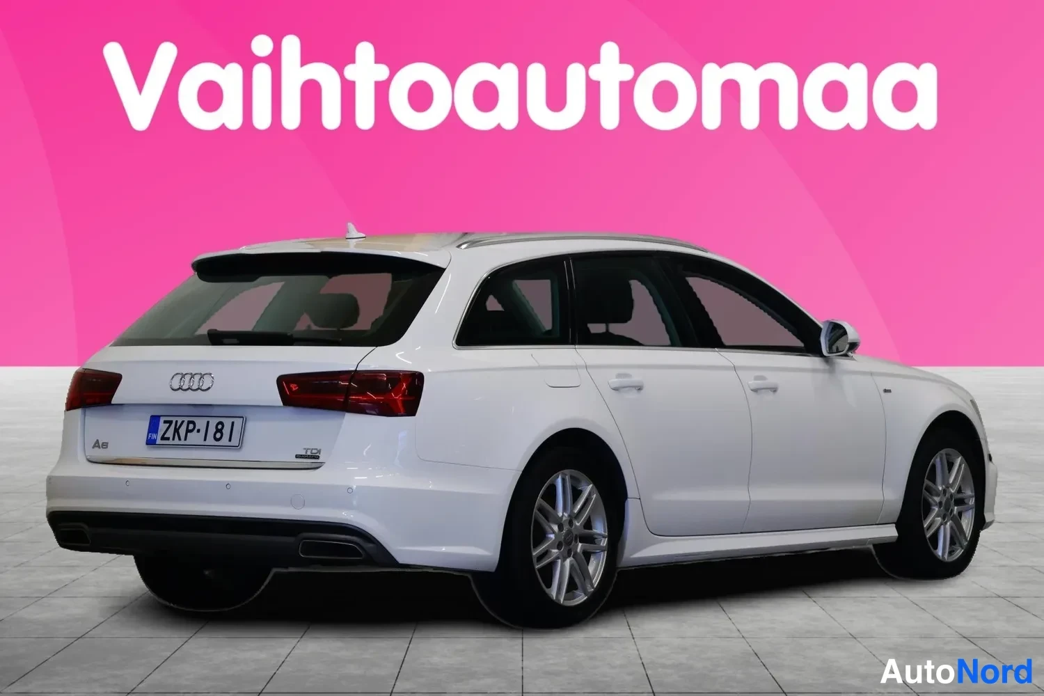 Takaviisto: Valkoisen Audi A6 Avant -farmarin takakulma oikealta