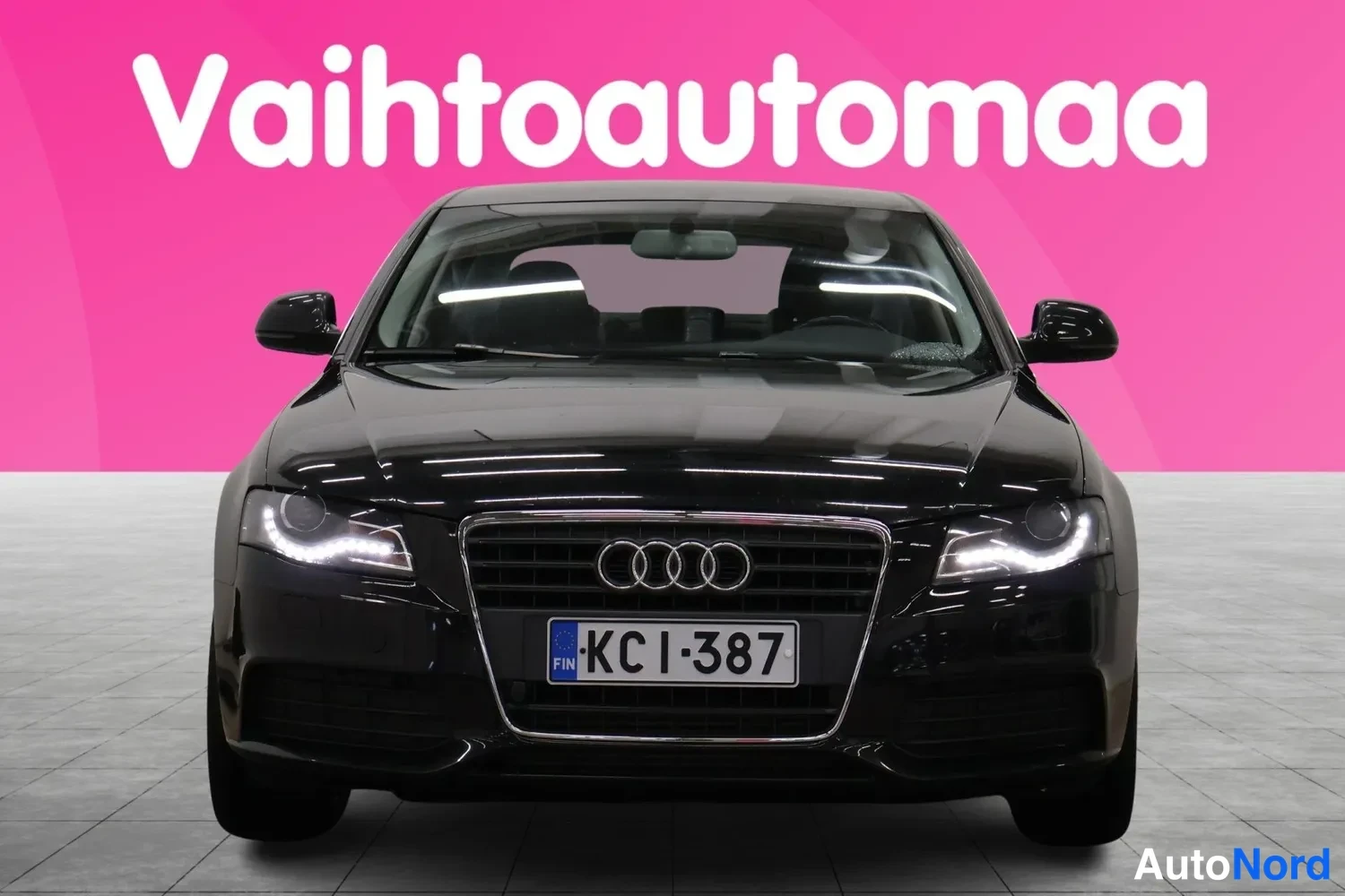 Edestä: Mustan Audi A4 -sedanin suora etunäkymä, etusäleikkö ja rekisteritunnus KC I-387 näkyvissä.