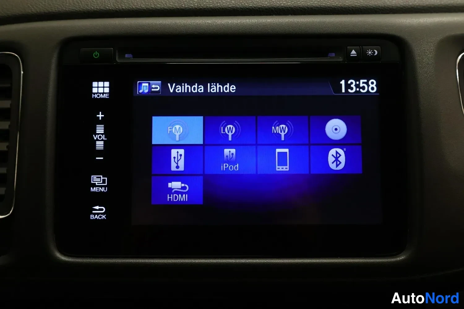 Muu: Värikosketusnäyttö näyttää lähdönvalintaikkunaa (Vaihda lähde) lähteillä FM, LW, MW, CD, USB, iPod, Phone, Bluetooth ja HDMI; kellonaika 13:58.