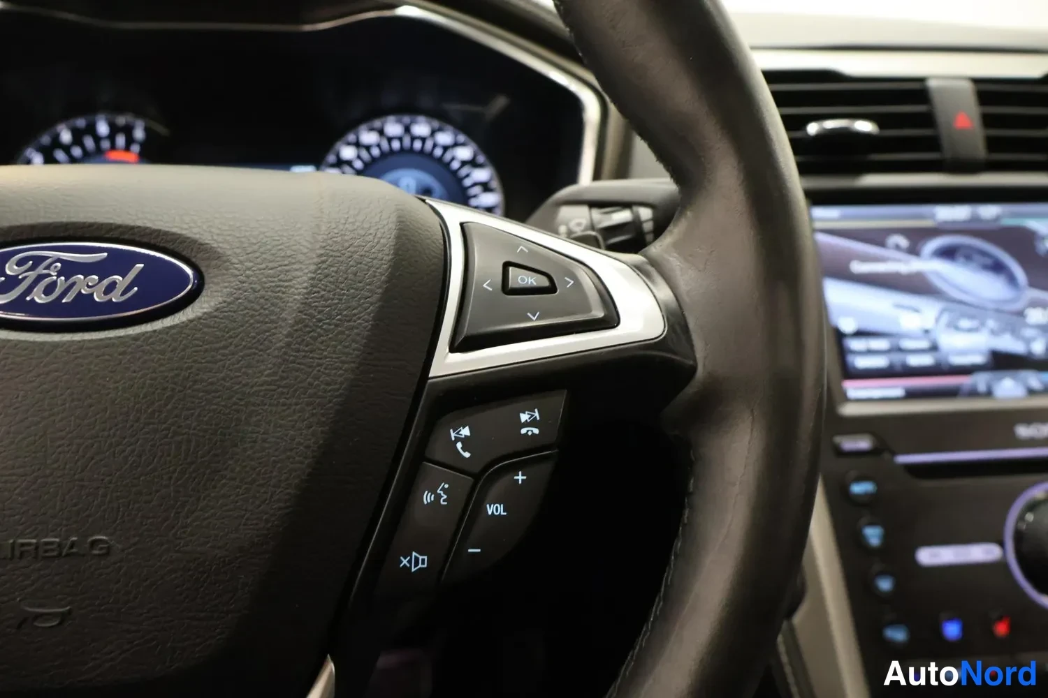 Muu: Ohjauspyörän Ford-logo ja monitoimipainikkeet, taustalla kojelauta ja osa keskikonsolista.