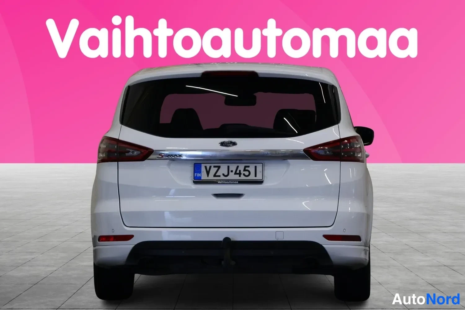 Takaa: Valkoisen tila-auton takaosa suoraan takaa kuvattuna, rekisteritunnus.