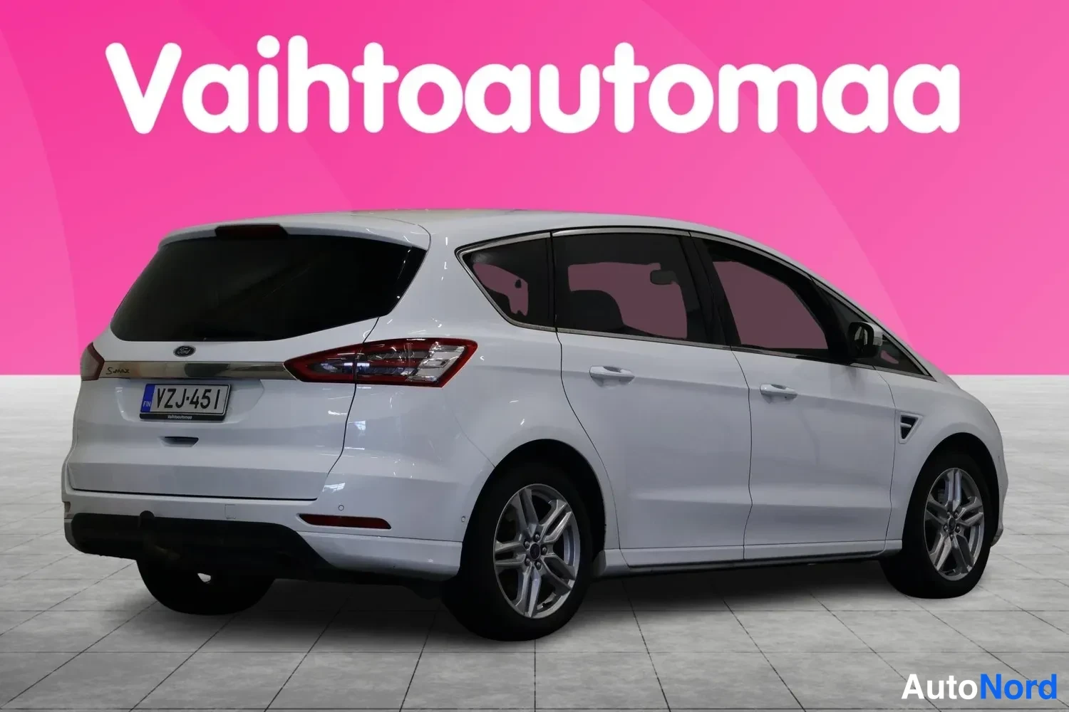 Takaviisto: Valkoinen tila-auto takaa vasemmalta oikealle kulmassa kuvattuna, rekisteritunnus.