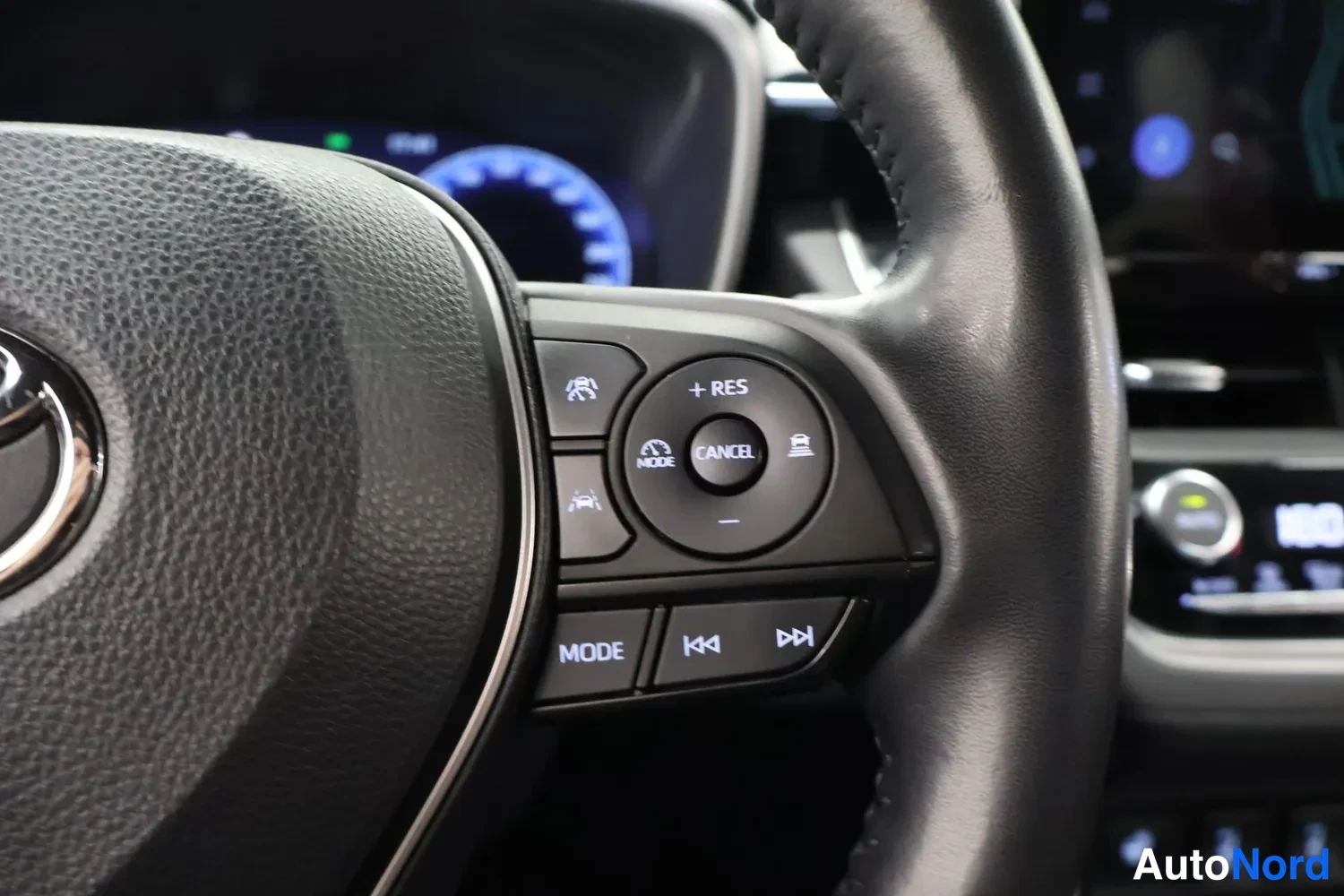 Yksityiskohta: Close-up of the steering wheel showing multifunction controls with buttons labeled RES, MODE, and track skip symbols.