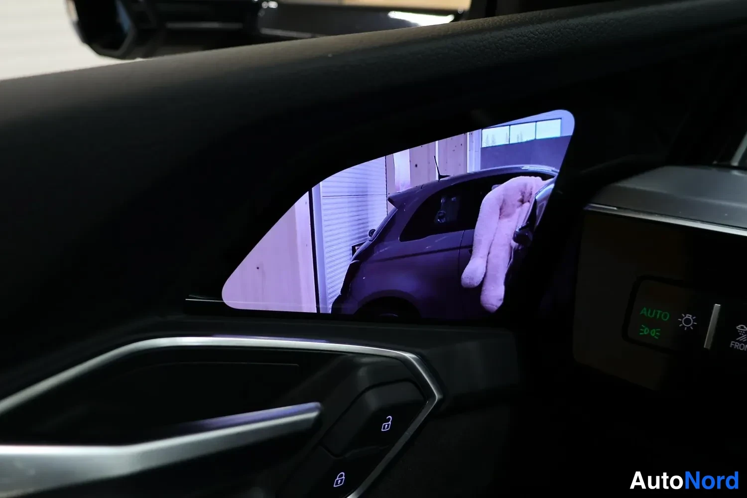 Muu: Oven sisäpaneelin digitaalinen sivupeilinäyttö, jonka kuva näyttää auton takaa; ovissa lukitusnappuloita ja-paneeli AUTO-merkillä.