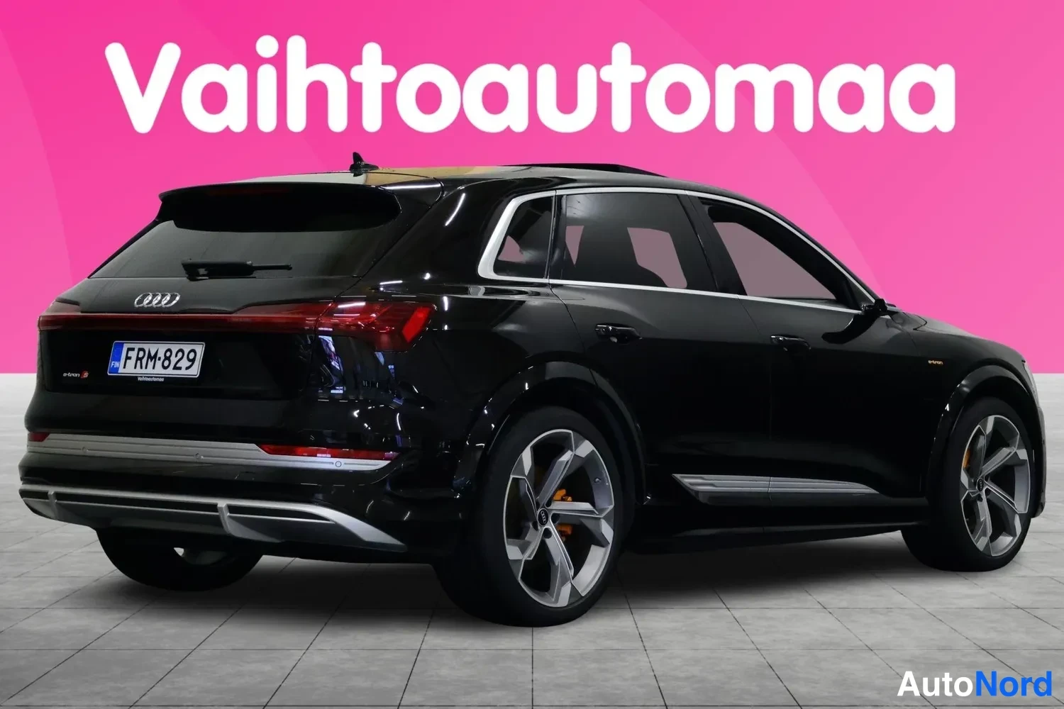 Takaviisto: Mustan SUV-auton takakulma, takavaloja ja rekisterikilpi näkyy pinkin taustan edessä.
