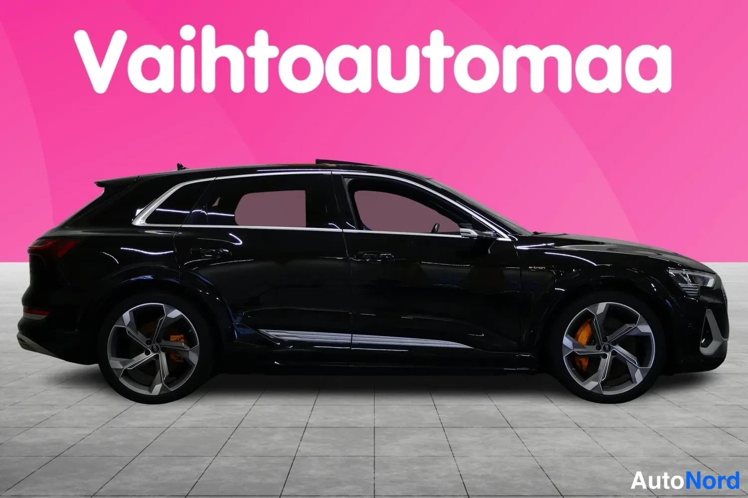 Etuviisto, nokka oikealle: Mustan SUV-auton sivukulma, keulan etumainen valoaine ja viisi reikää näkyvät oikeassa reunassa pinkin taustan edessä.