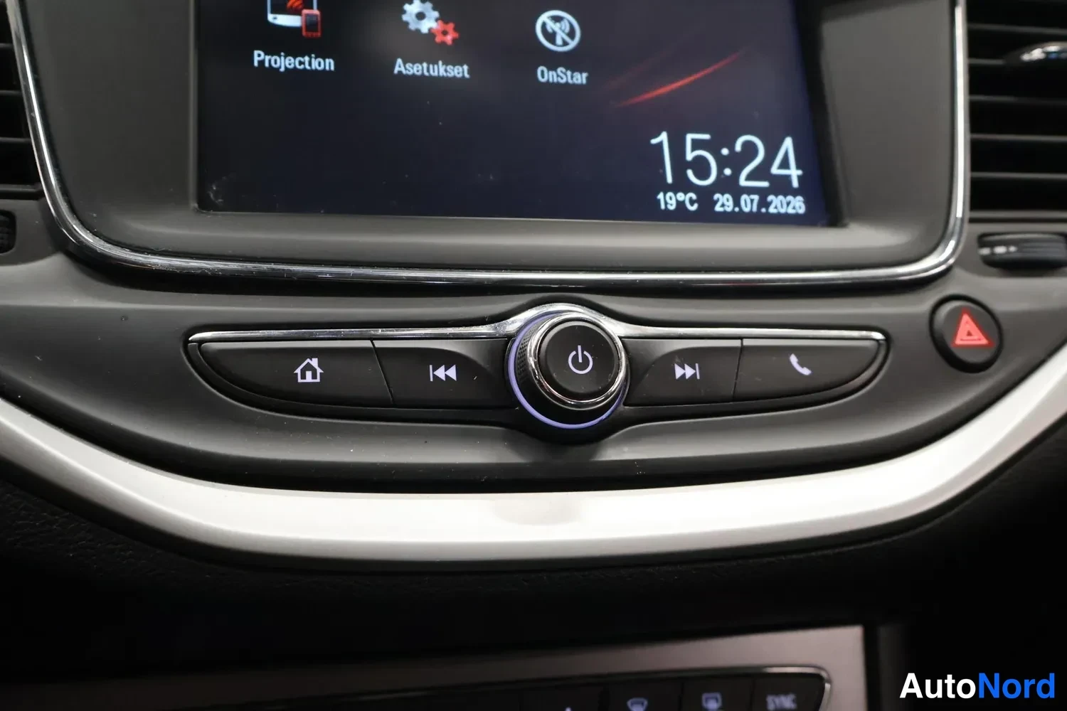 Yksityiskohta: Infotainment-näytön valikko jossa kohdat Projection, Asetukset ja OnStar, sekä kello 15:24 ja lämpötila 19°C.
