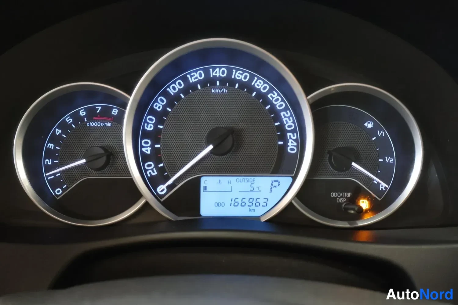 Yksityiskohta: Mittaristö lähikuvassa: nopeusmittari, kierroslukumittari ja polttoainemittari; matkamittari näyttää 166363 km.