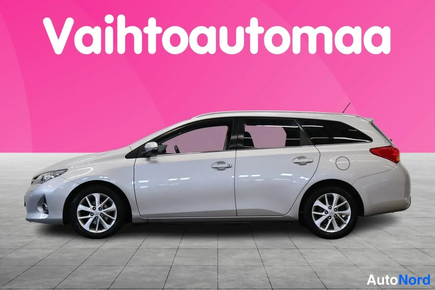 Etuviisto, nokka vasemmalle: Hopeanharmaa Toyota Auris -farmari sivulta etukulmasta, keula kuvan vasemmassa reunassa.