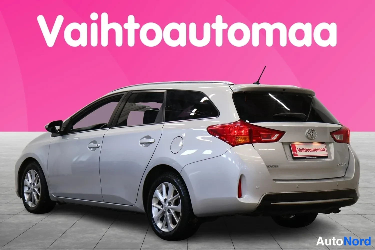 Takaviisto: Hopeanharmaan Toyota Auris -farmarin takaosa ja oikea kylki takaviistosta, takavalot ja nokkakoriste näkyvissä.