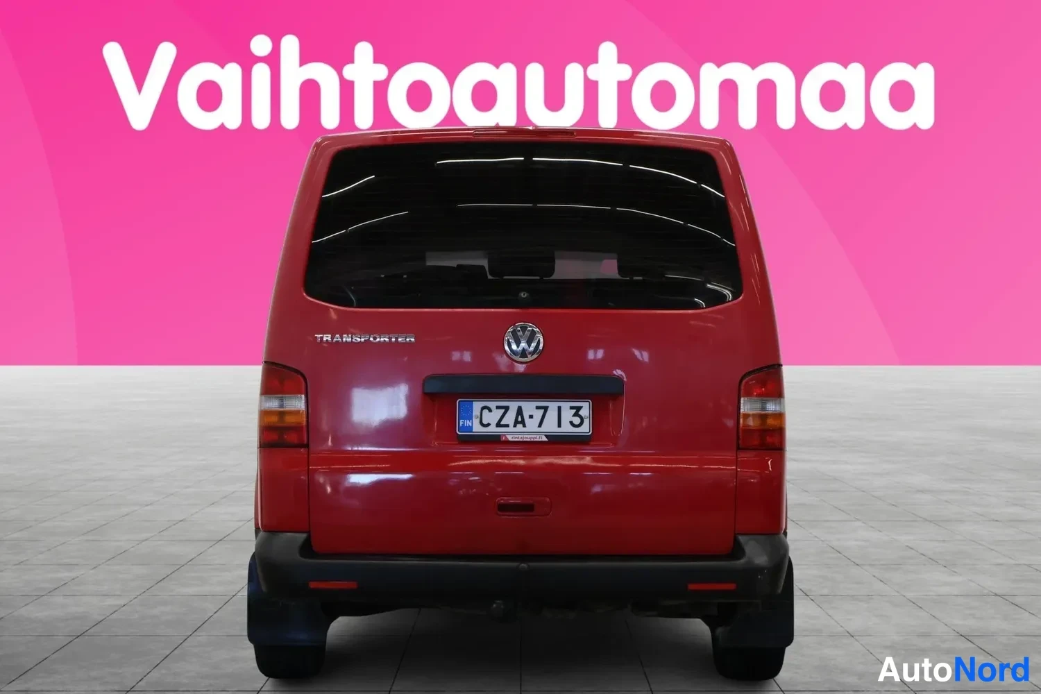 Takaa: Punaisen Volkswagen Transporter -pakettiauton takanäky, rekisterikilpi, pinkki tausta.