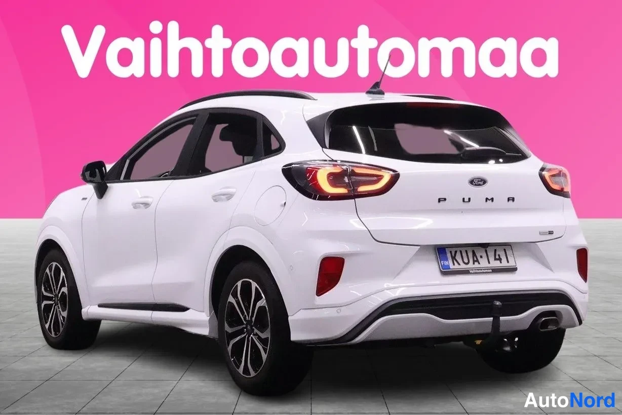 Takaviisto: Valkoinen Ford Puma takakulmasta, PUMA-teksti ja rekisterikilpi, pinkki tausta.
