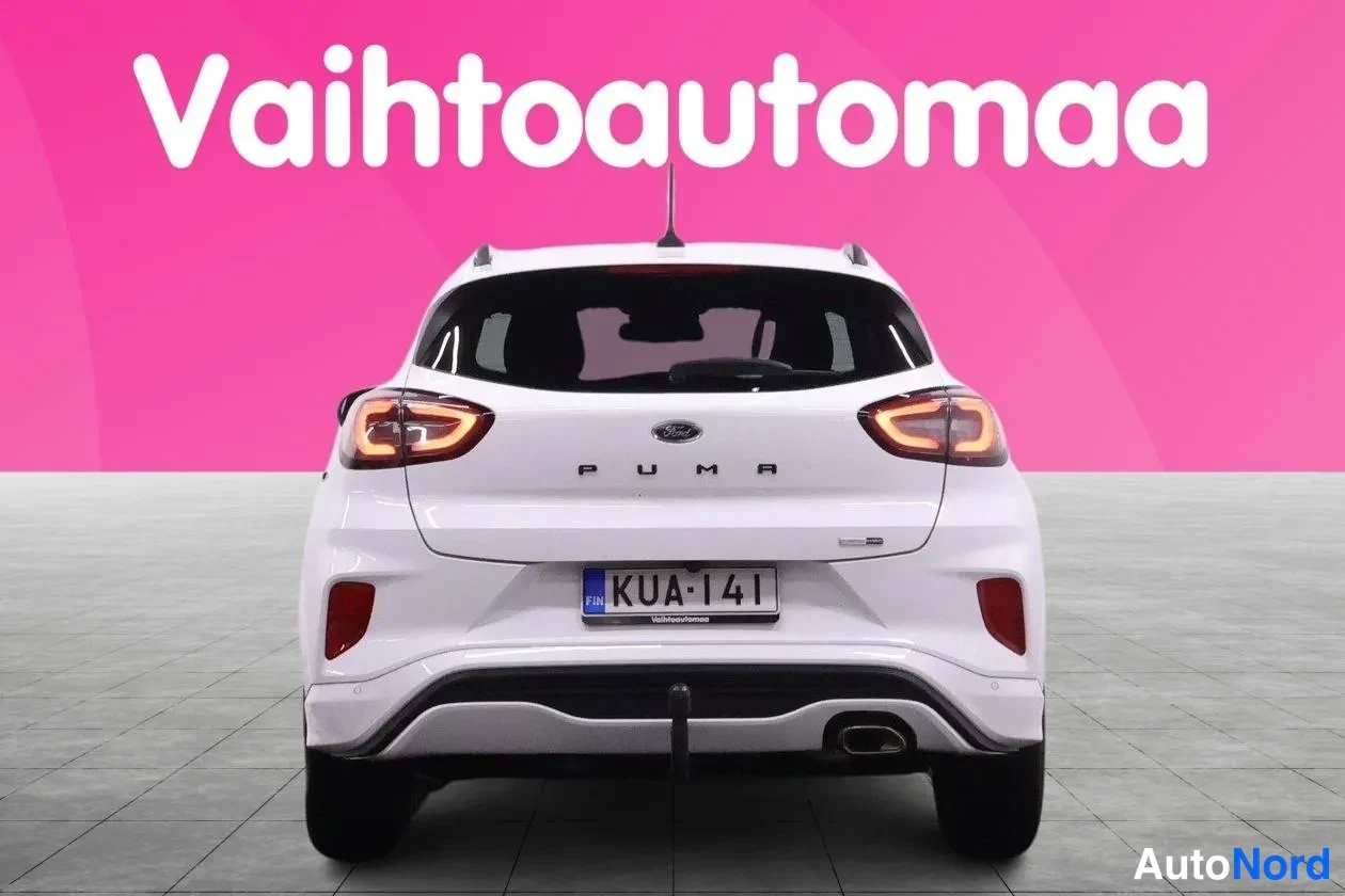 Takaa: Valkoinen Ford Puma suoraan takaa, PUMA-teksti ja rekisterikilpi, pinkki tausta.