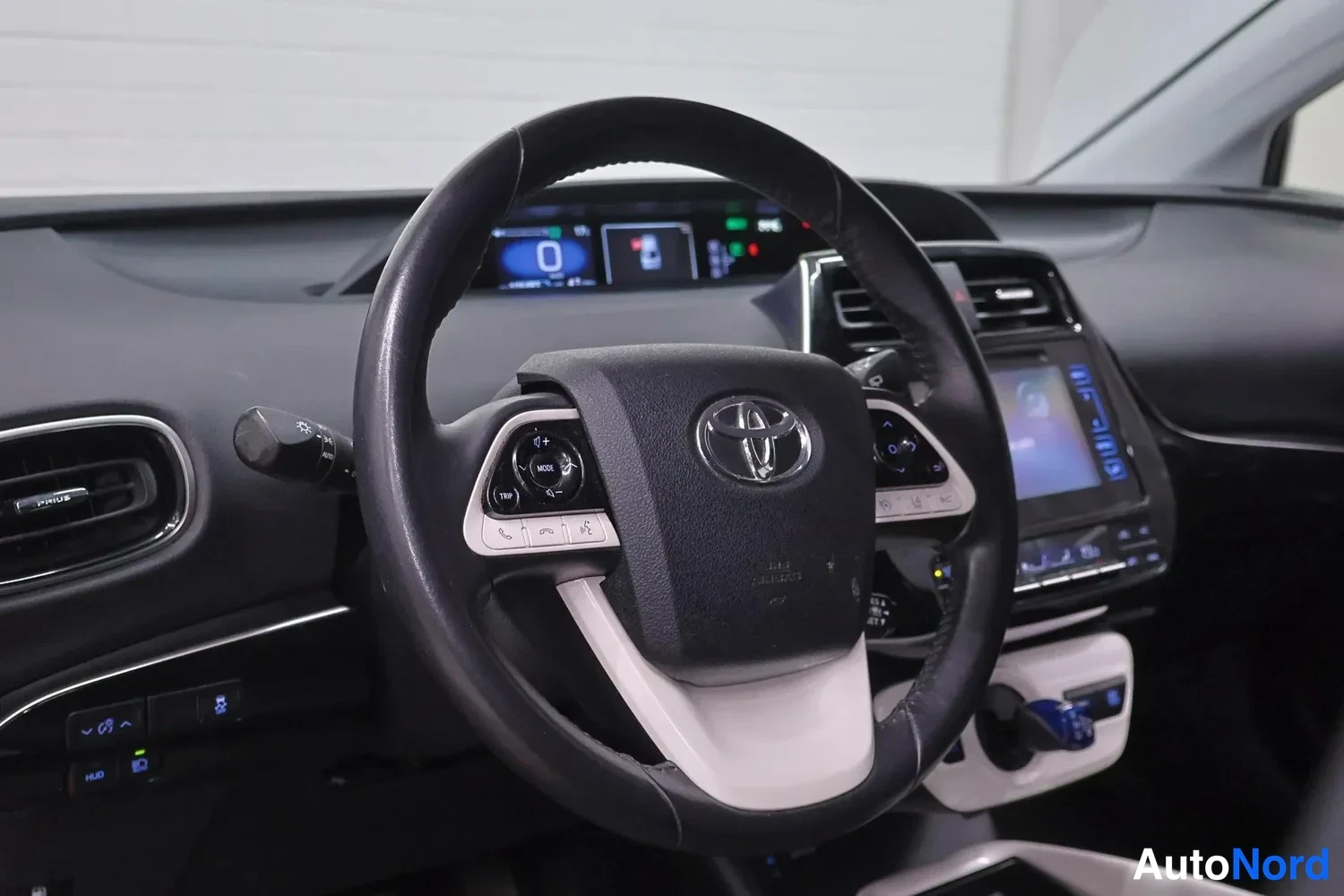 Muu: Lähikuva Toyotan merkillisestä ohjauspyörästä ja kojelaudasta, mittariston näyttö ja keskikonsolin infotainment-näyttö näkyvät.