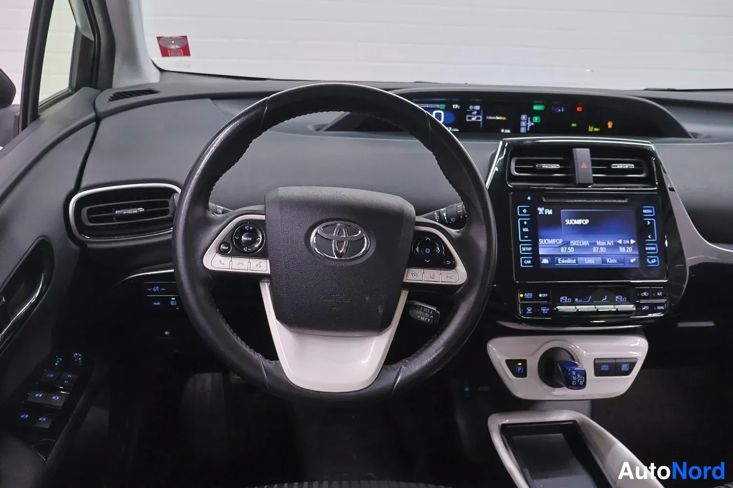 Muu: Toyota-ohjauspyörä, kojelaudan näytöt ja keskikonsolin infotainment-näyttö, jolla lukee SUOMPOP 87.50.