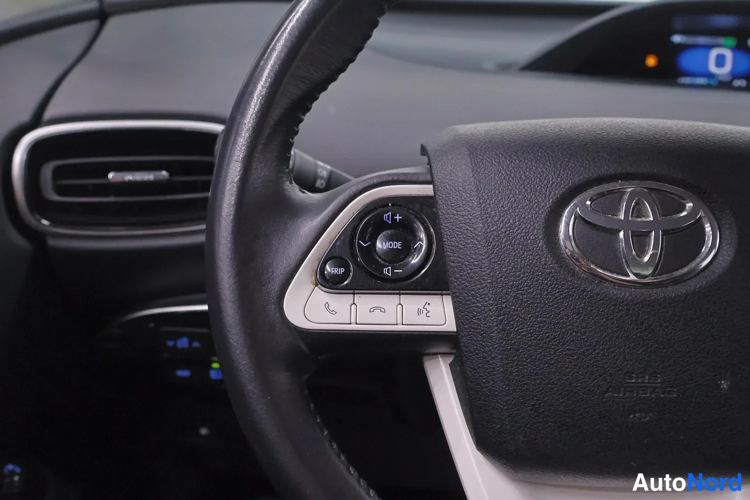 Muu: Sisäkuva Toyota-ohjauspyörästä ja sen vasemman puolen painikkeista, teksti SRS AIRBAG näkyvissä.