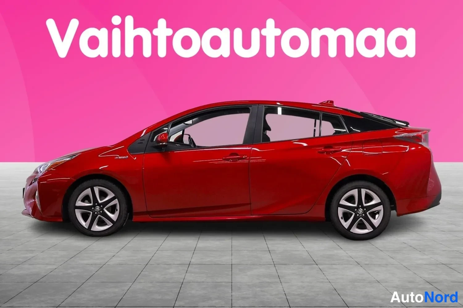 Etuviisto, nokka vasemmalle: Punainen Toyota Prius sivulta, etuosa vasemmassa reunassa.