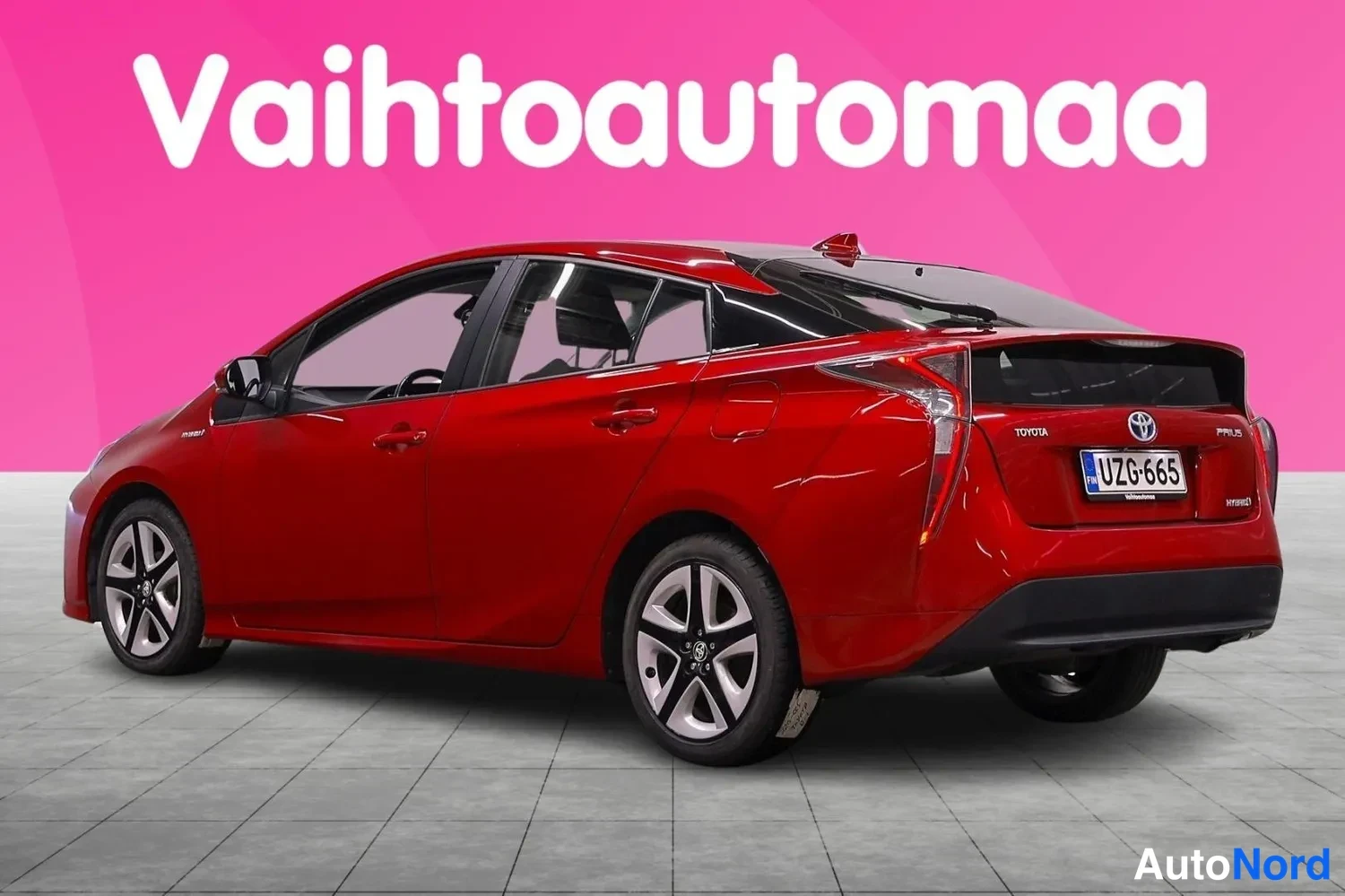 Takaviisto: Punainen Toyota Prius takaviistosta, rekisteritunnus, takavaloissa näkyy Toyota- ja Prius-merkinnät.